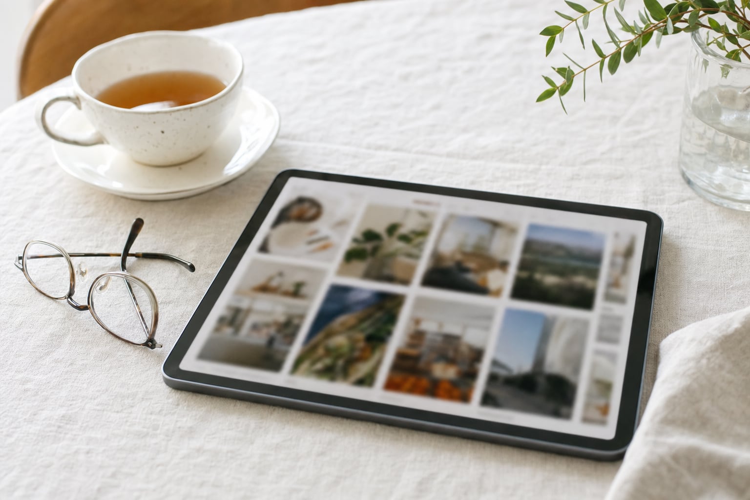 A tablet on a table beside a cup of tea, showing a grid of article cards