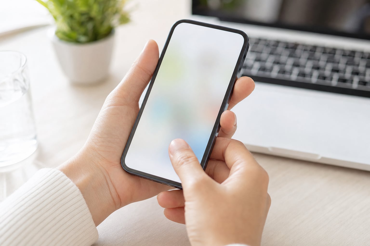 A person holding a phone above a desk, about to tap the screen